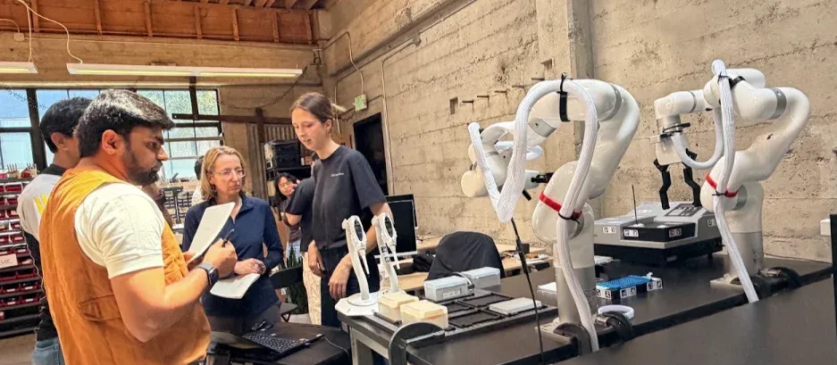 Builders working beside robotic arms on a closed-loop biology project