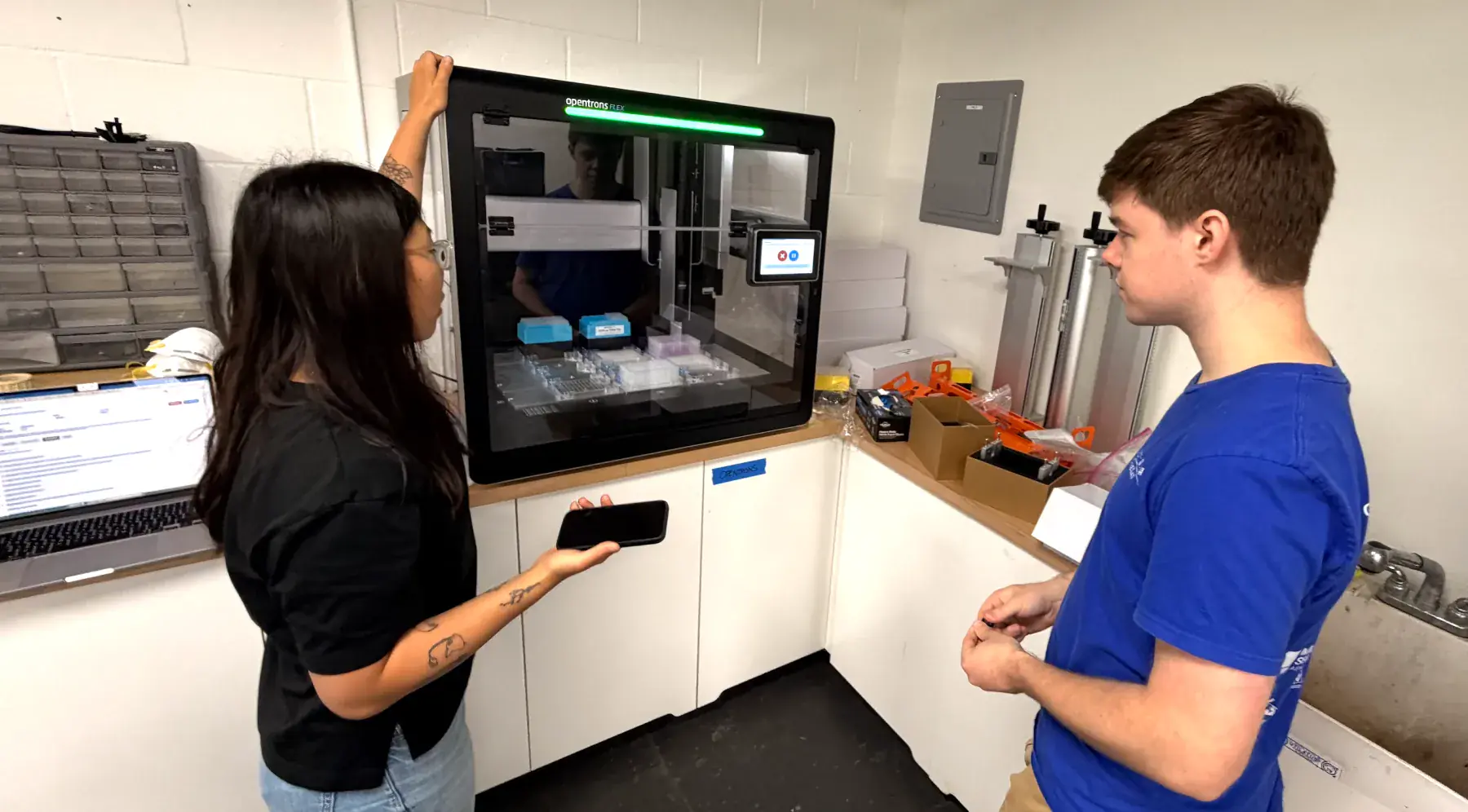 Two fellows working with an Opentrons lab automation robot